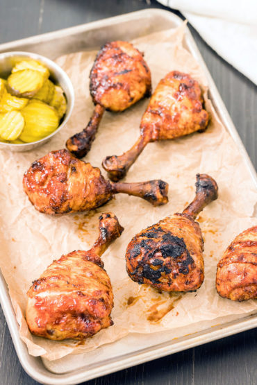 Chicken lollipops and pickles on a baking sheet.